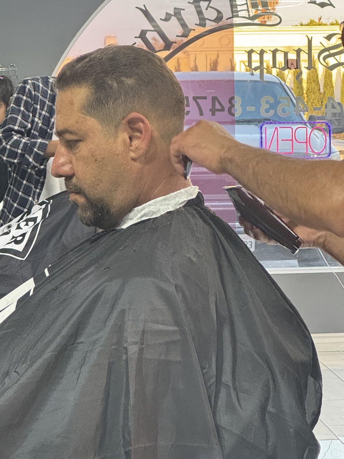 Barber at work, neon Open sign in the window