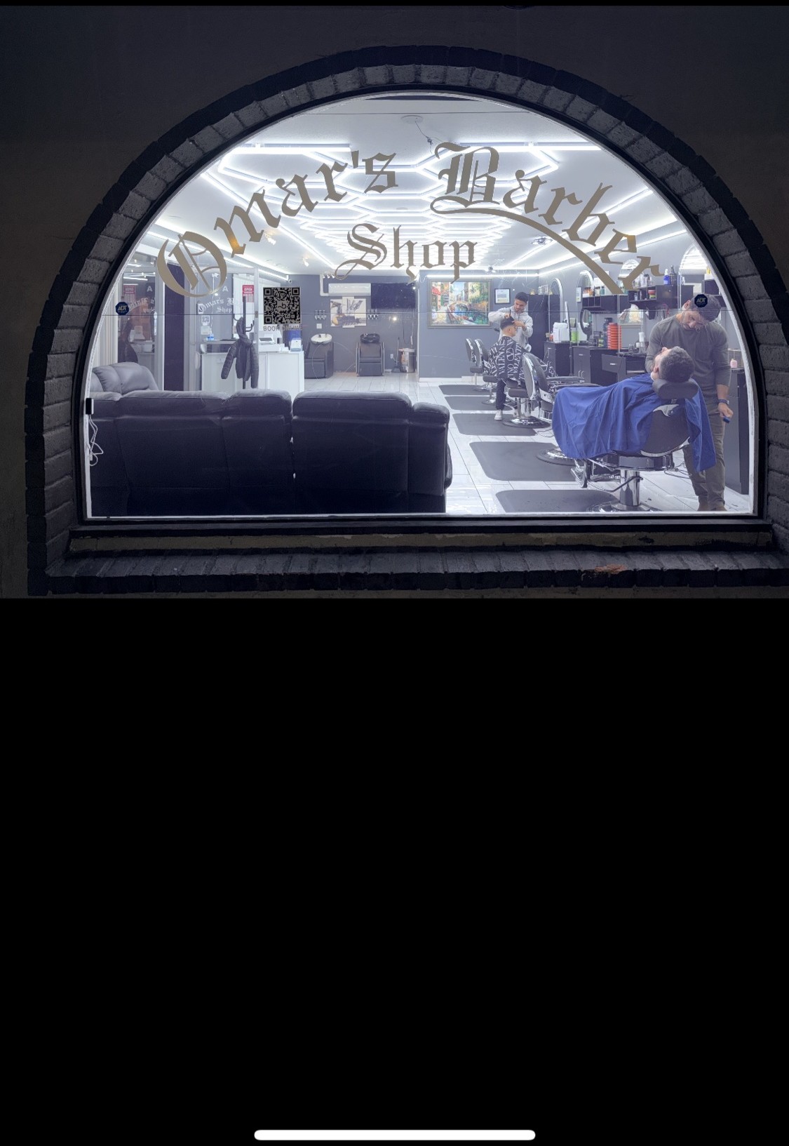 Omar's Barbershop glowing through the arched window at night